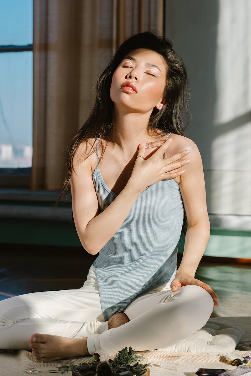 Woman meditating indoors, embracing spirituality with natural sunlight. Perfect for wellness and mindfulness themes.